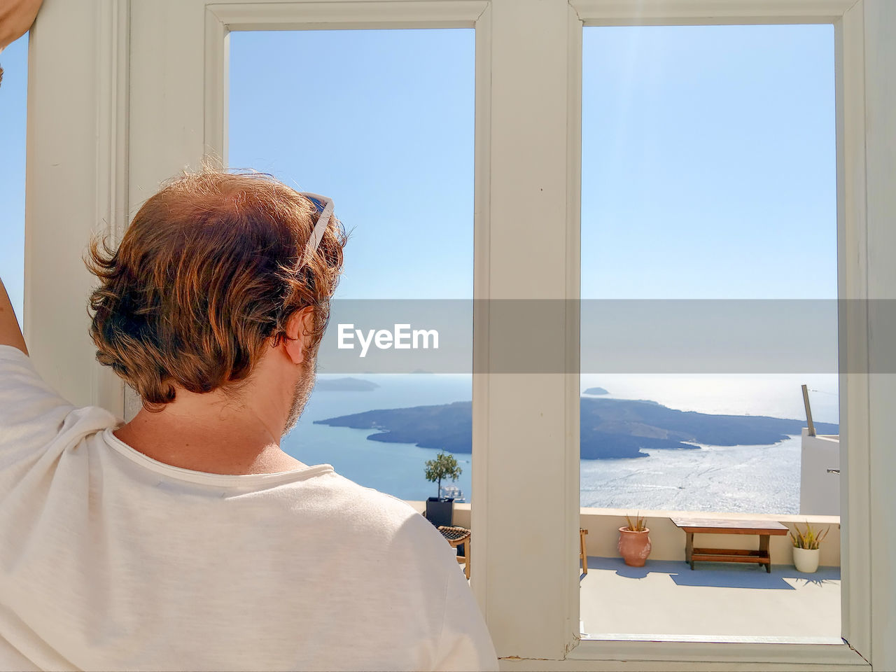 Rear view of man looking scenic view through window