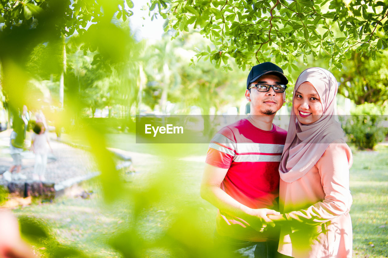 Portrait of smiling young couple standing at park