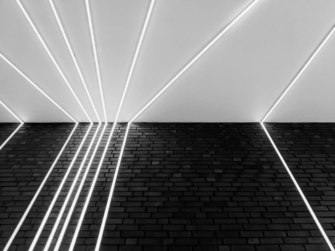 Low angle view of illuminated fluorescent lights on wall and ceiling