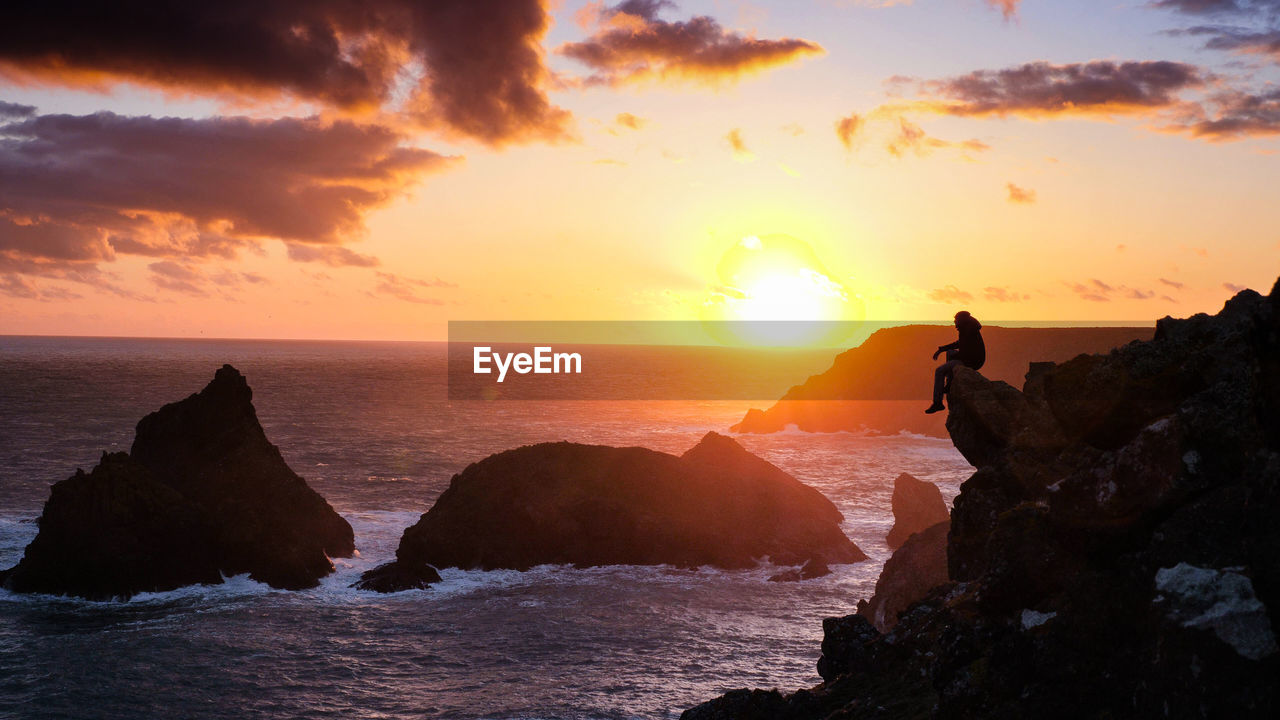 SCENIC VIEW OF ROCKS IN SEA AGAINST SKY DURING SUNSET