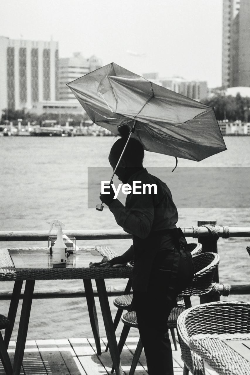 Waitress holding umbrella cleaning table at restaurant