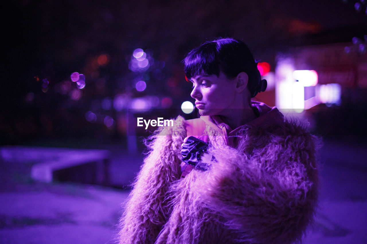 Young woman looking away at night during winter