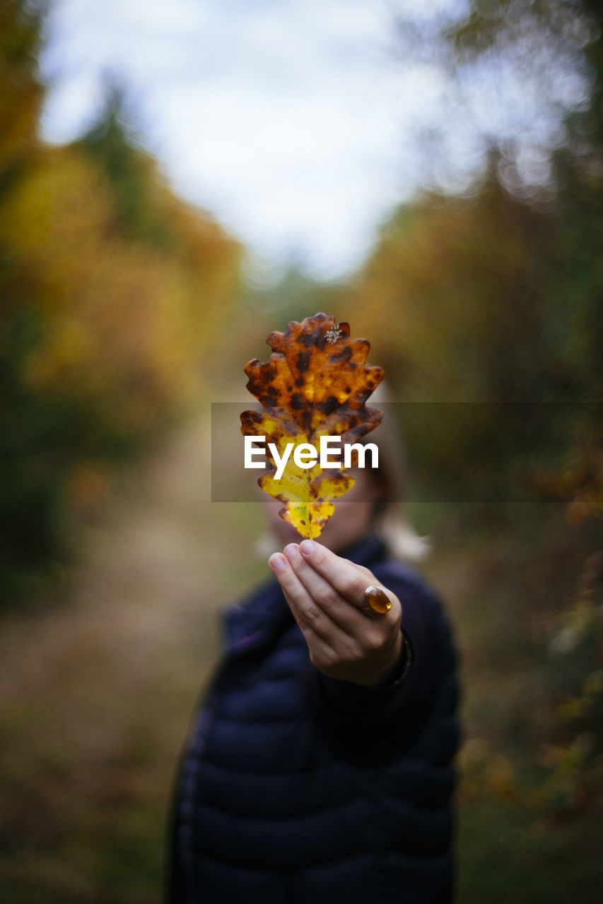 Woman showing autumn leaf in park