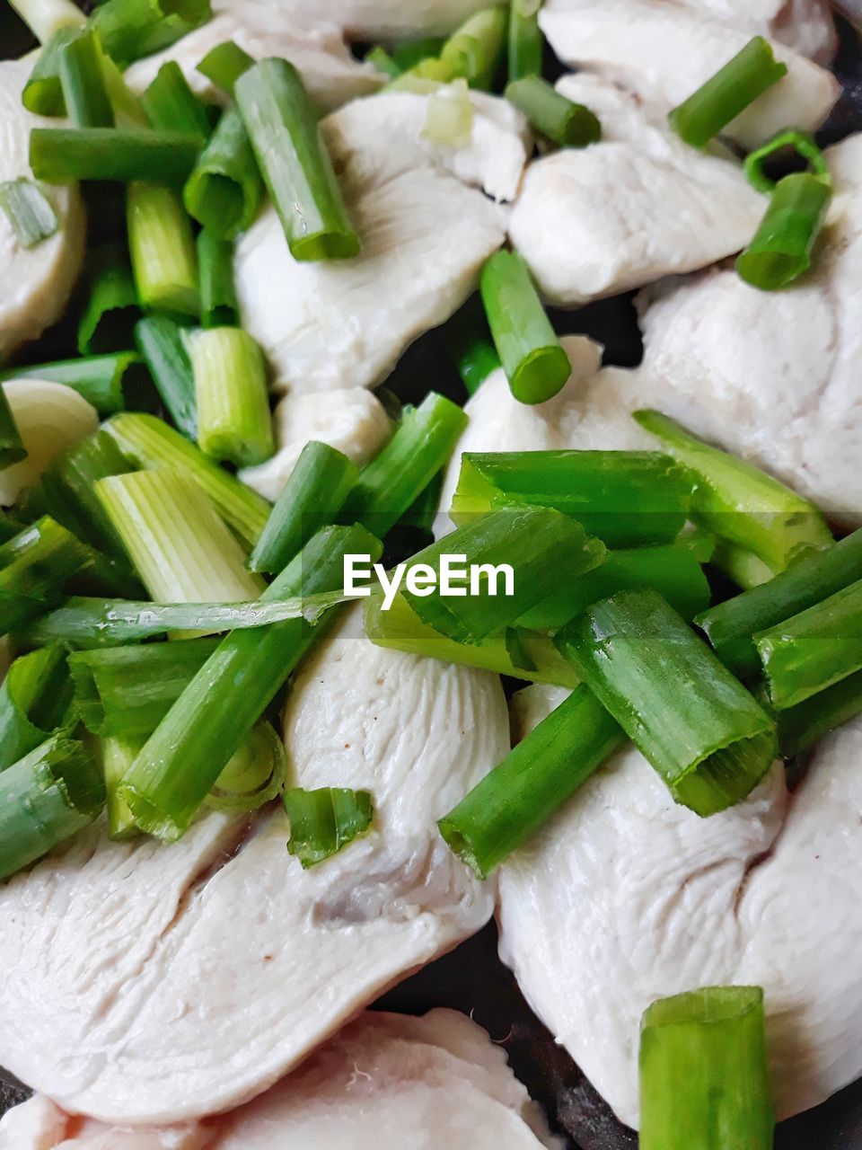 Full frame shot of chopped spring onions
with white chicken fillet. white meat with scallion
