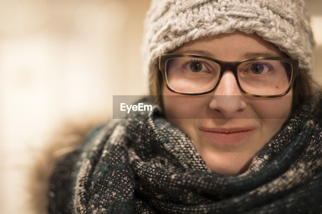 Close-up portrait of beautiful woman wearing scarf and knit hat with eyeglasses