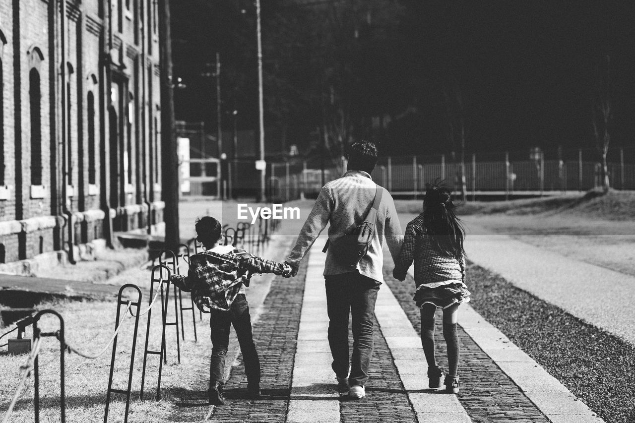 Rear view of father with son and daughter walking on footpath