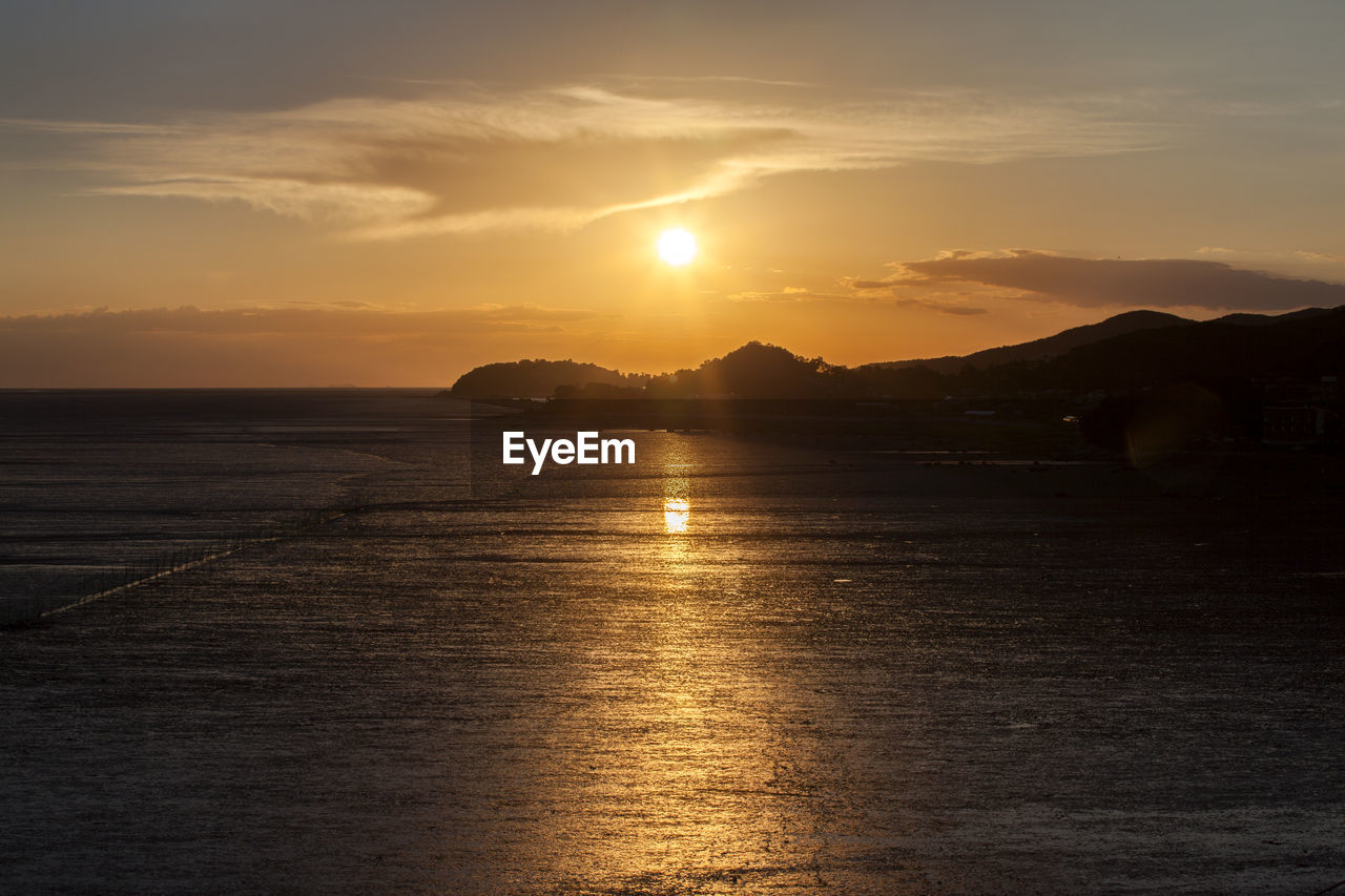 Scenic view of river with silhouetted mountains at dusk