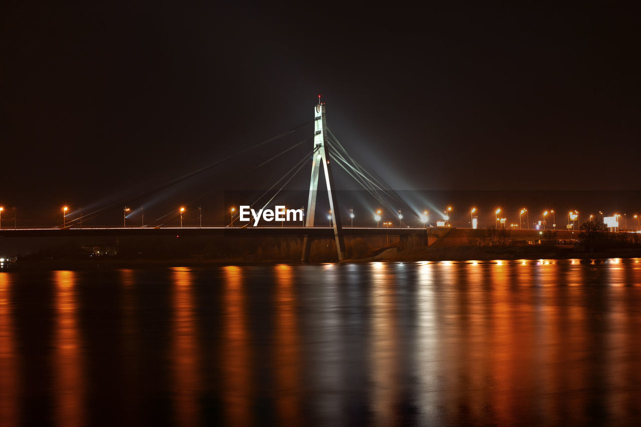 ILLUMINATED BRIDGE OVER RIVER WITH REFLECTION IN BACKGROUND