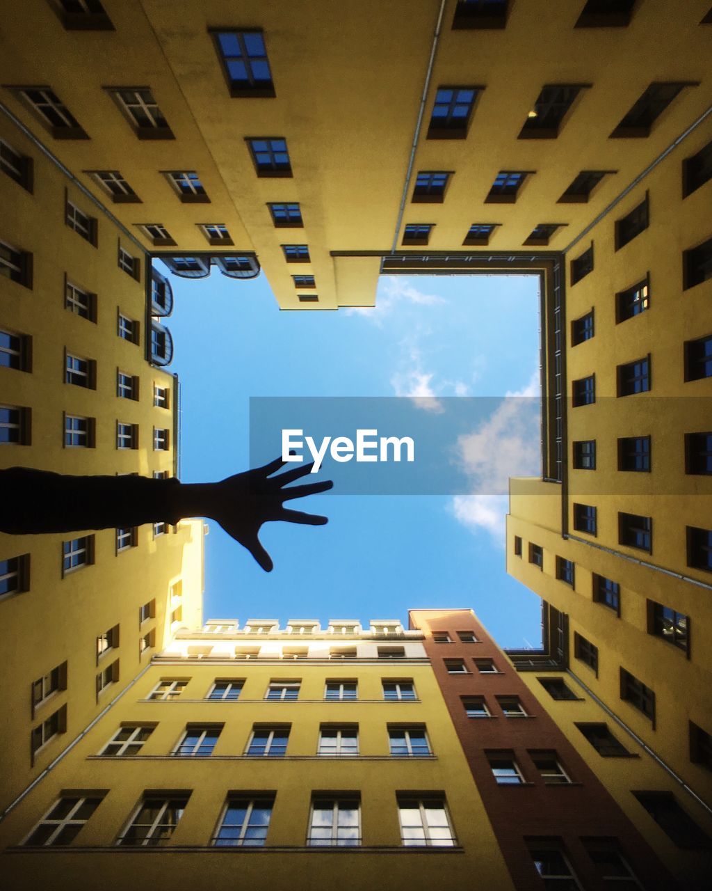 Directly below shot of buildings with silhouette cropped hand