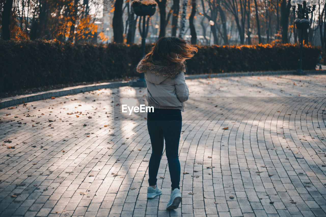 Rear view of woman standing on footpath