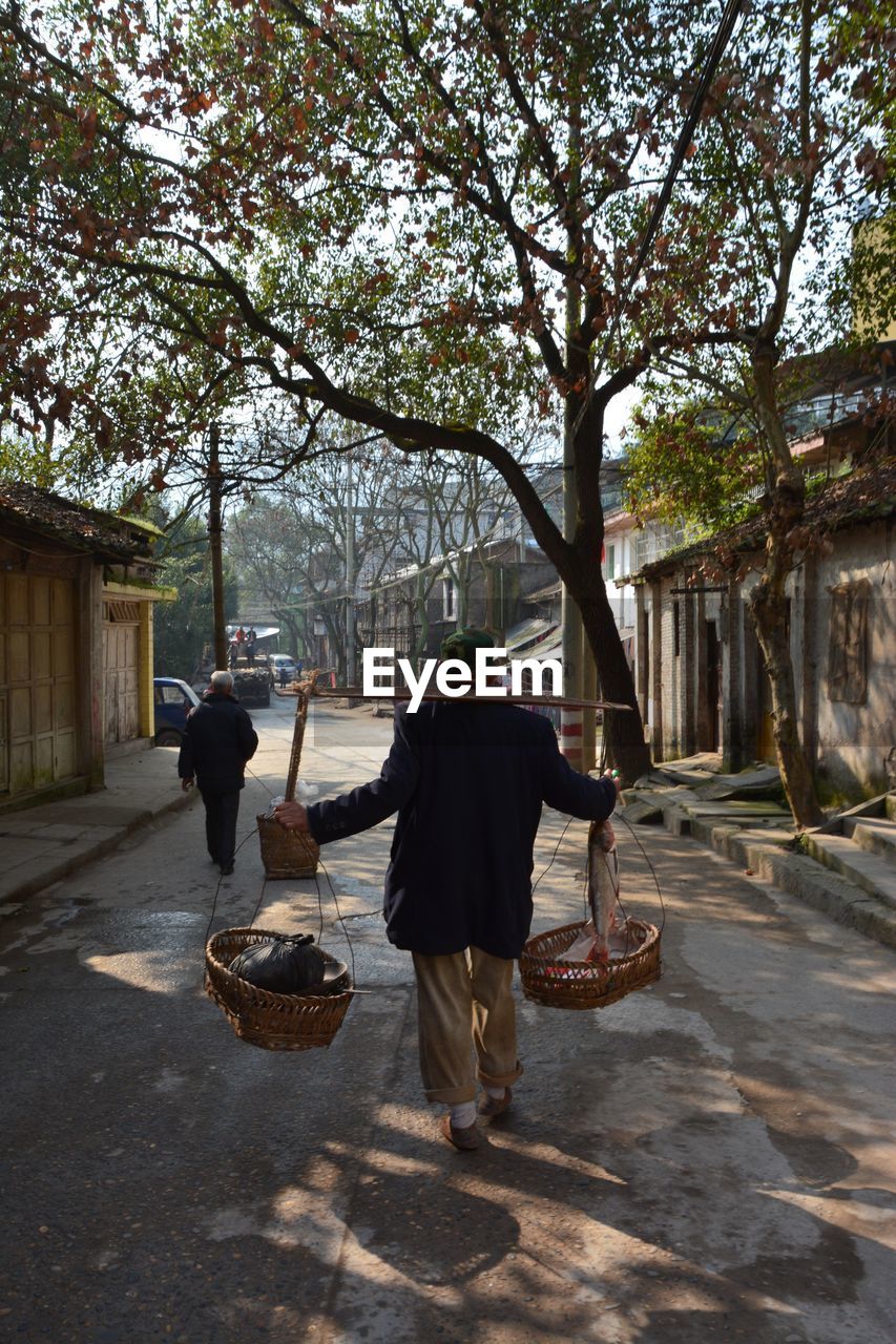 Full length rear view of vendor walking on street