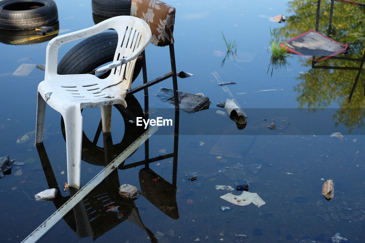 Broken chairs and tires in water on field