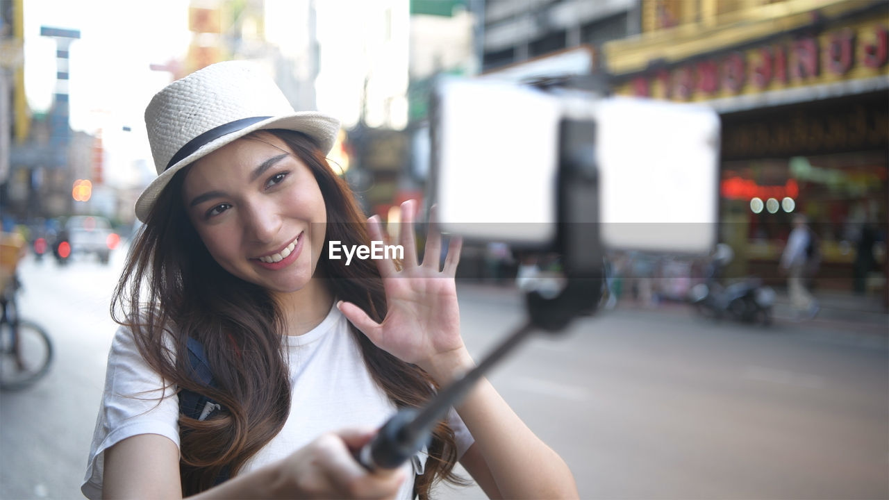 PORTRAIT OF SMILING YOUNG WOMAN IN STREET