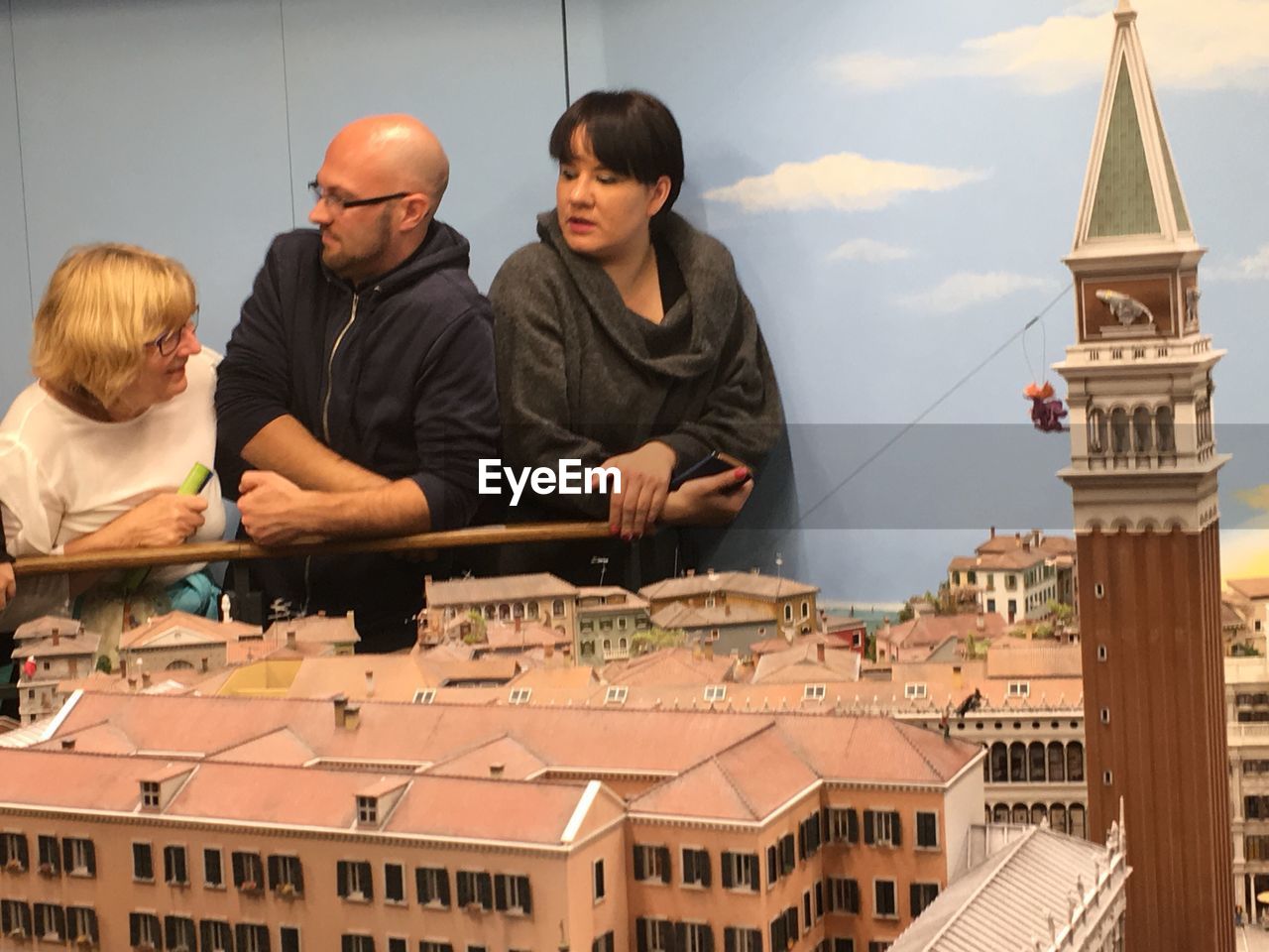 PEOPLE STANDING BY BUILDING IN CITY AGAINST SKY