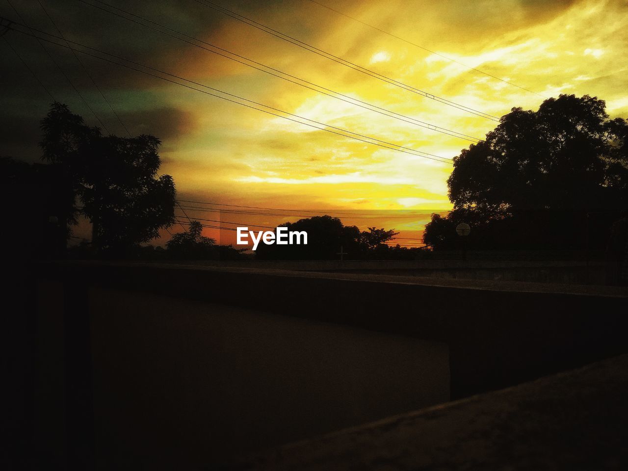 CLOSE-UP OF WET SILHOUETTE LANDSCAPE AGAINST SKY DURING SUNSET