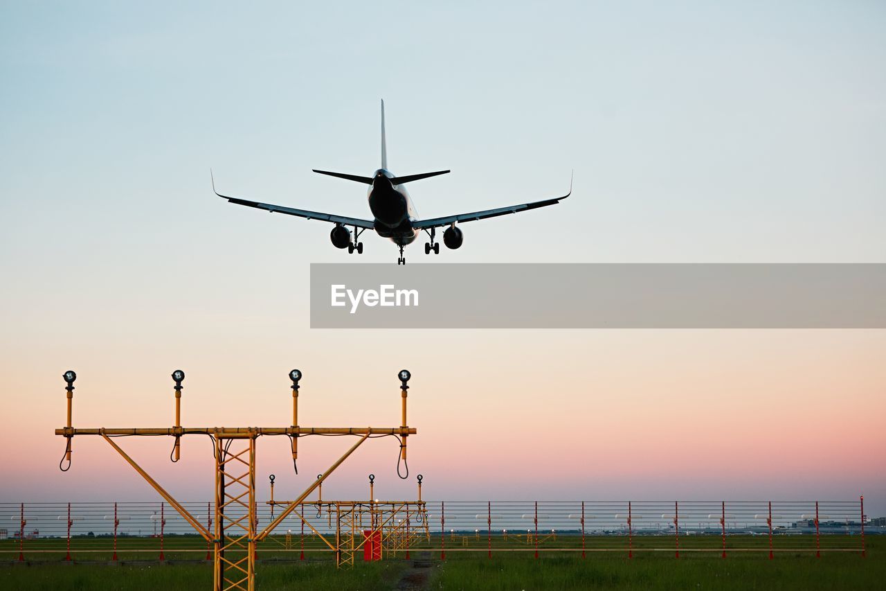 Airplane landing at airport runway during sunset