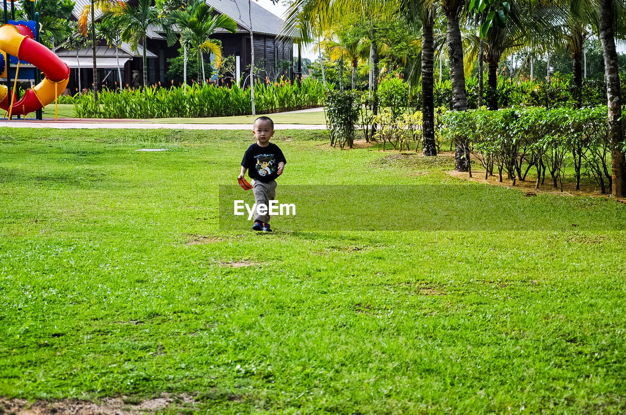 Boy walking on grassy field at park