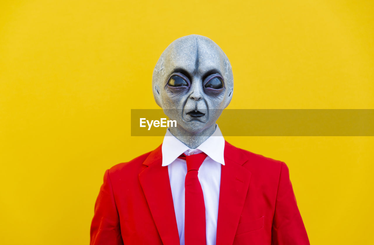 Portrait of man wearing alien costume and bright red suit