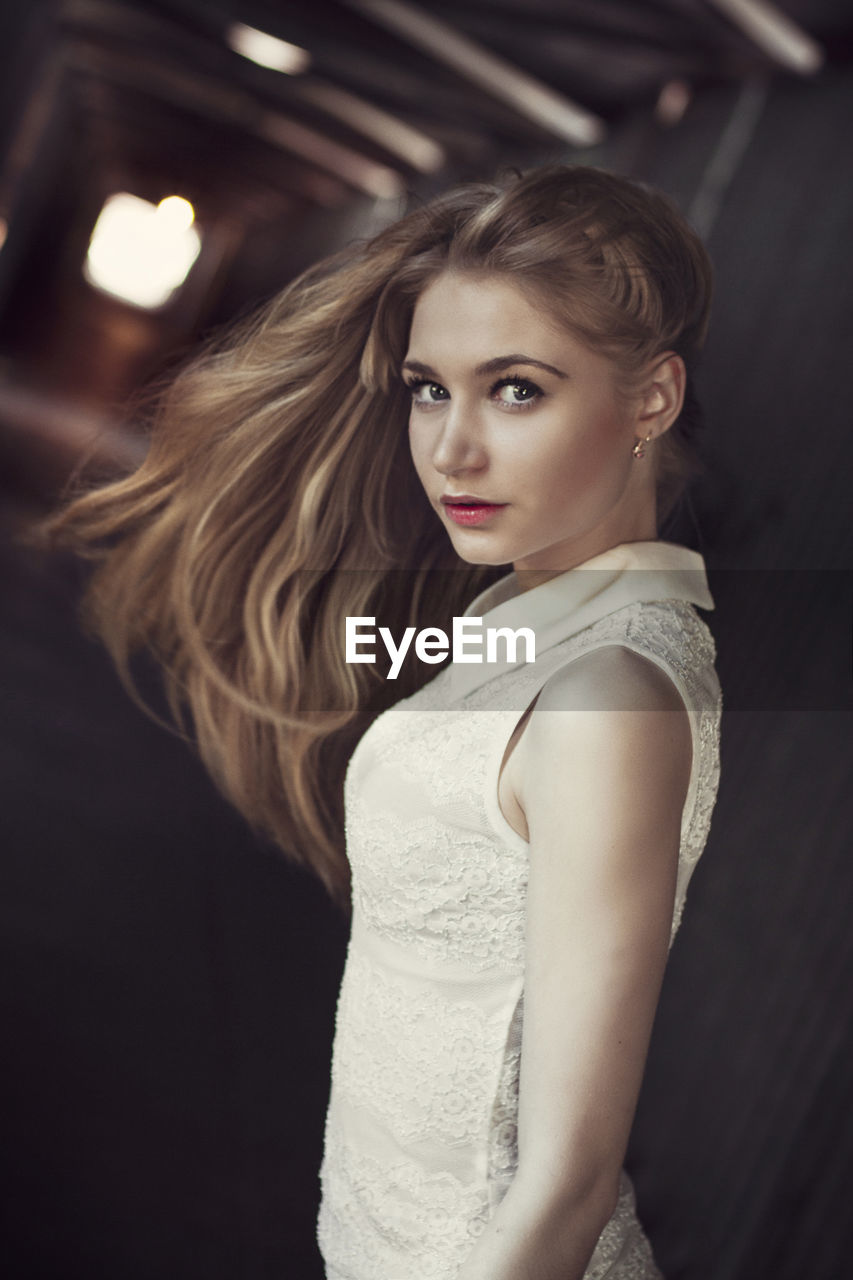 Portrait of young woman against black background