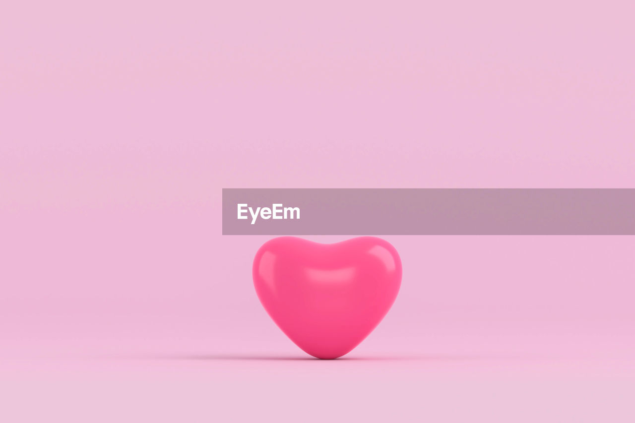 Close-up of heart shape balloon over pink background