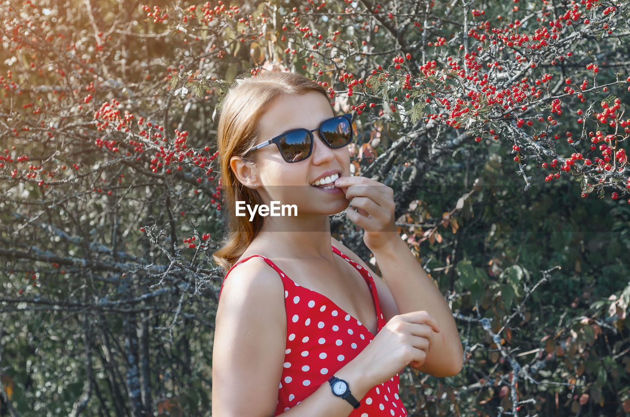 Young woman near bush with red hawthorn berries. smile, natural beauty