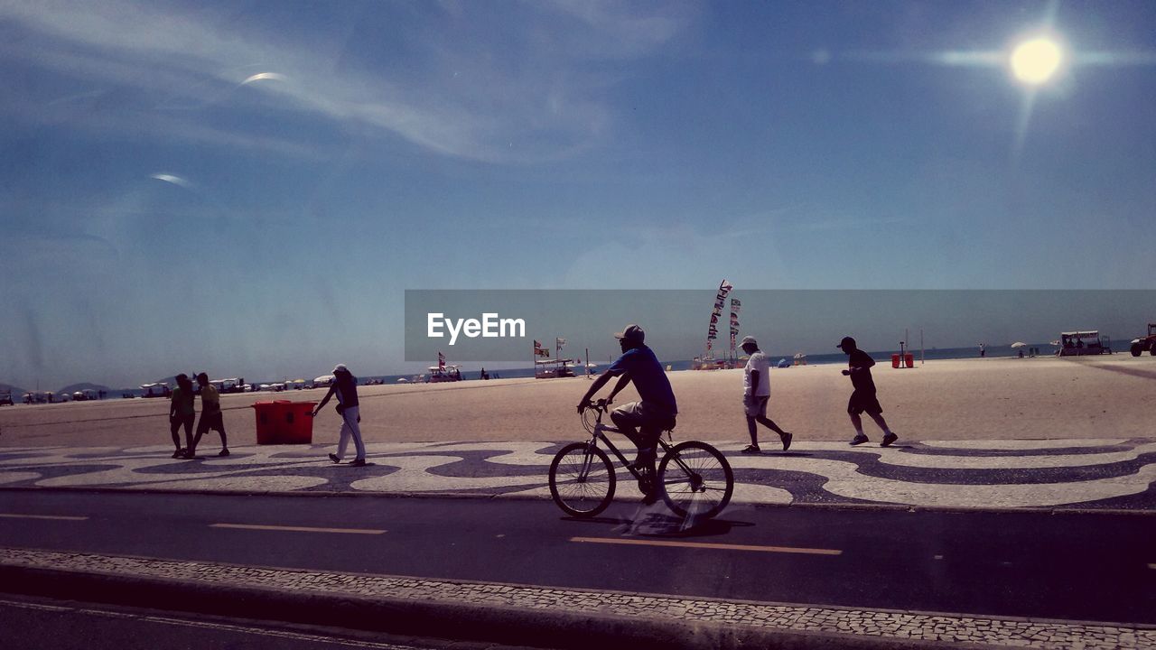VIEW OF PEOPLE ON BICYCLE AT BEACH