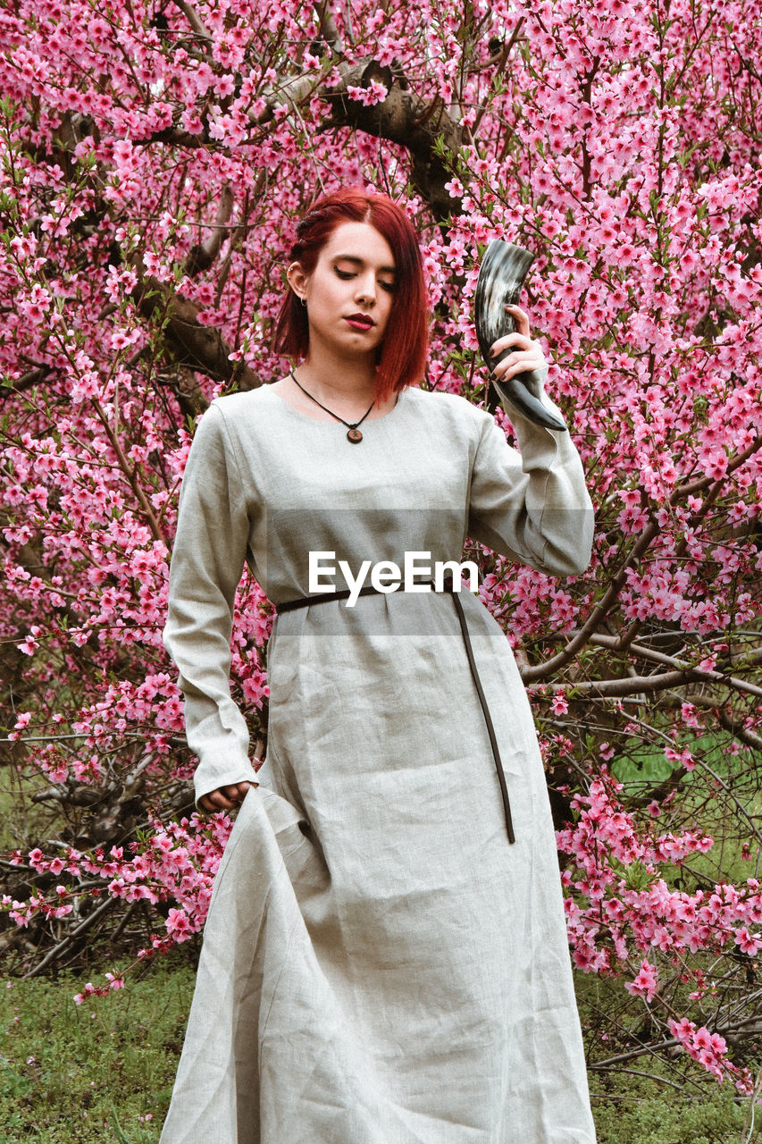 Portrait of young woman standing against plants