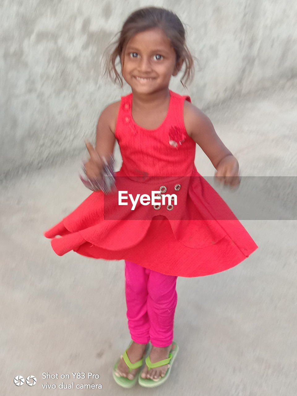 PORTRAIT OF A SMILING GIRL STANDING OUTDOORS