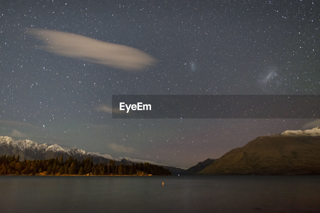 SCENIC VIEW OF LAKE AGAINST MOUNTAIN AT NIGHT