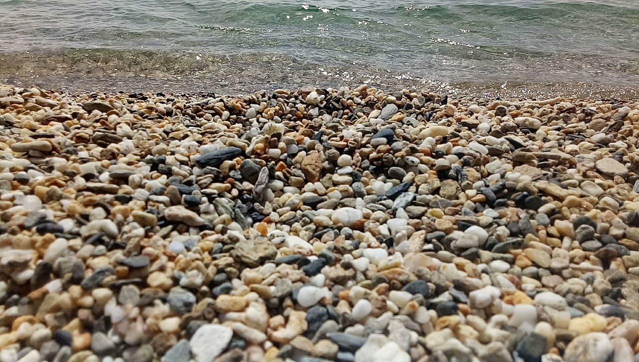 CLOSE-UP OF PEBBLES AT BEACH