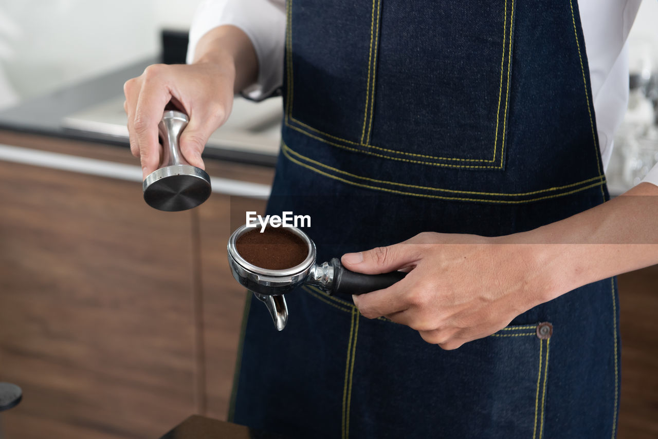 Close up of hand of barista man holding coffee tamper with grind coffee for making coffee 