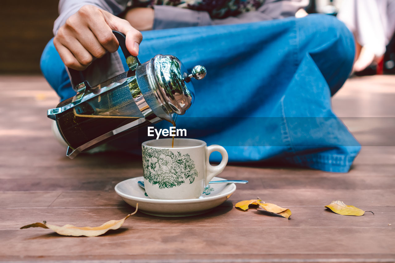 Pour french coffee into a cup. glass on a wooden table