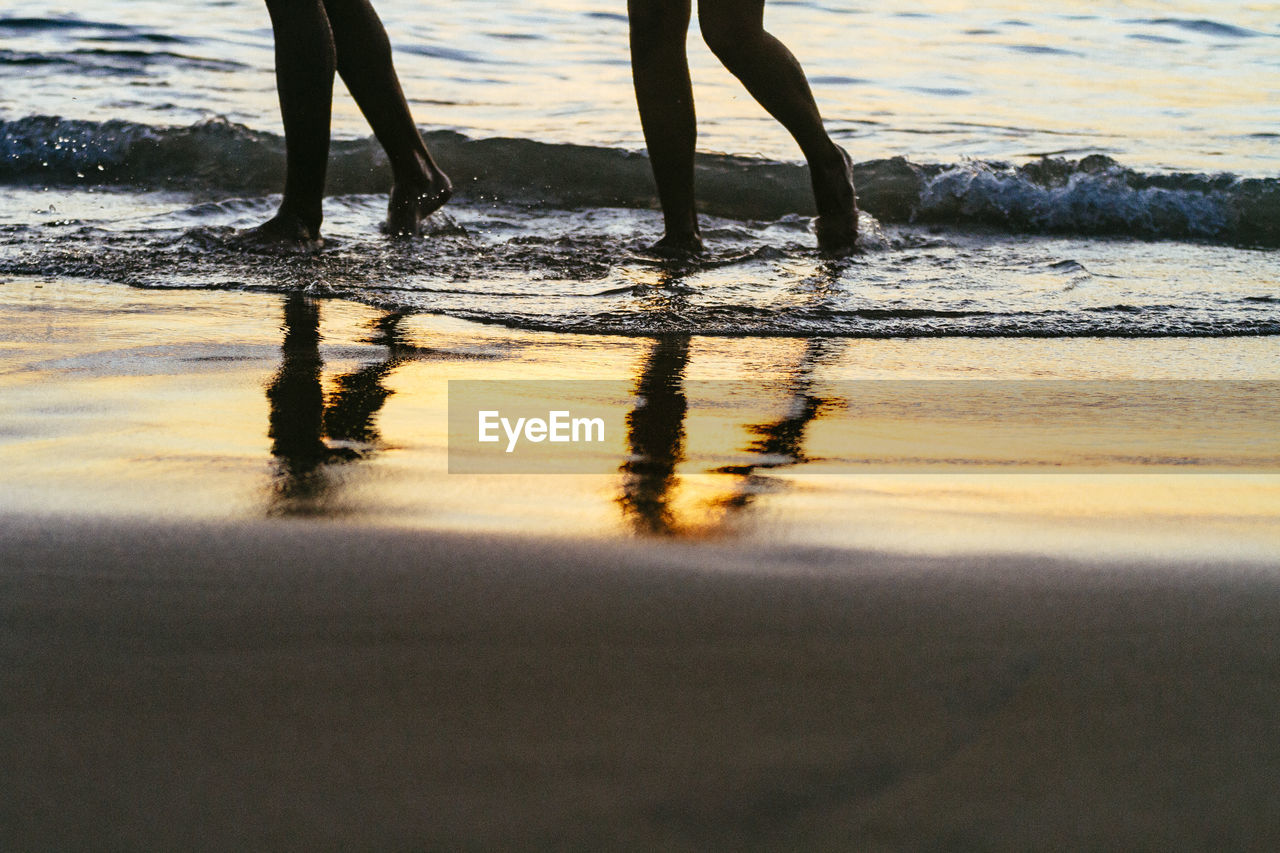 LOW SECTION OF PEOPLE WALKING ON SHORE