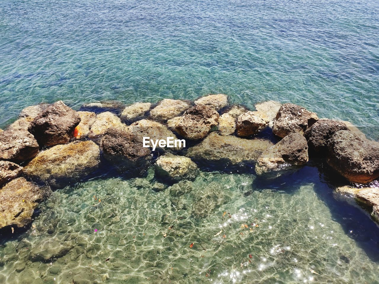 HIGH ANGLE VIEW OF ROCKS ON SHORE AT SEA