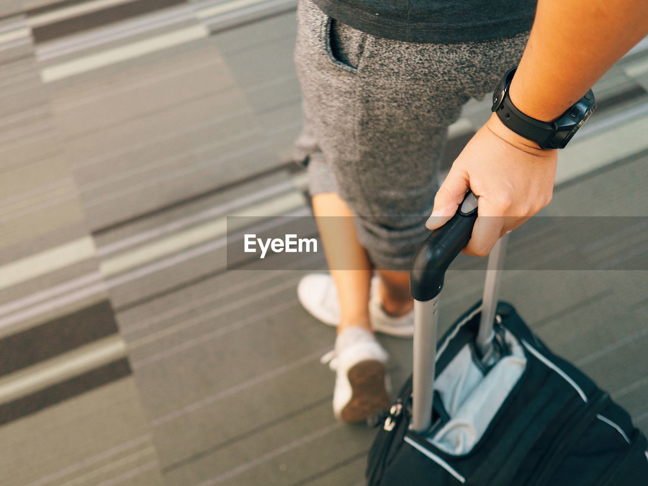 Low section of woman holding luggage while standing on floor