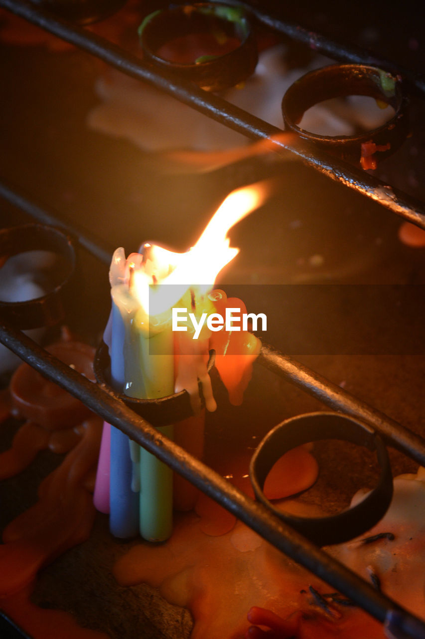 HIGH ANGLE VIEW OF LIT CANDLES ON TABLE