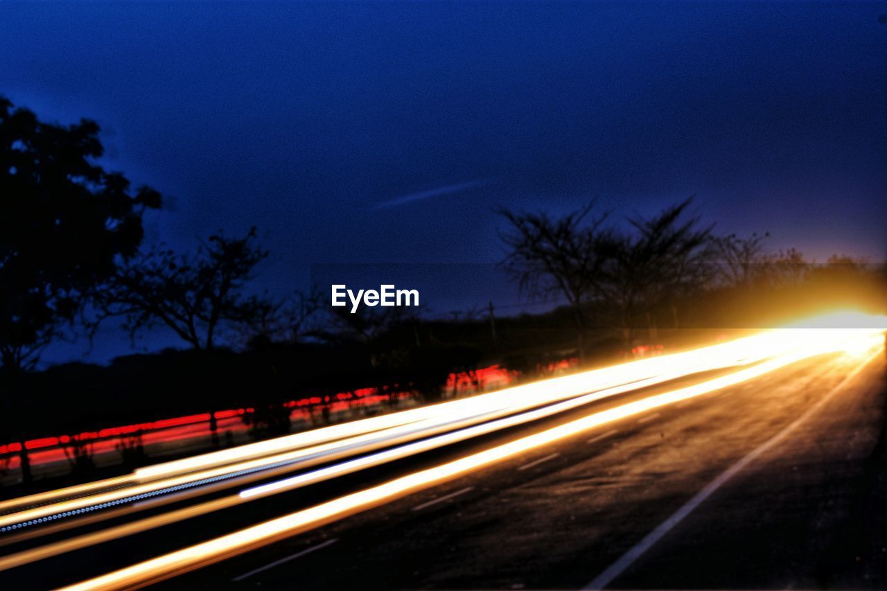 ILLUMINATED LIGHT TRAILS ON ROAD AT NIGHT