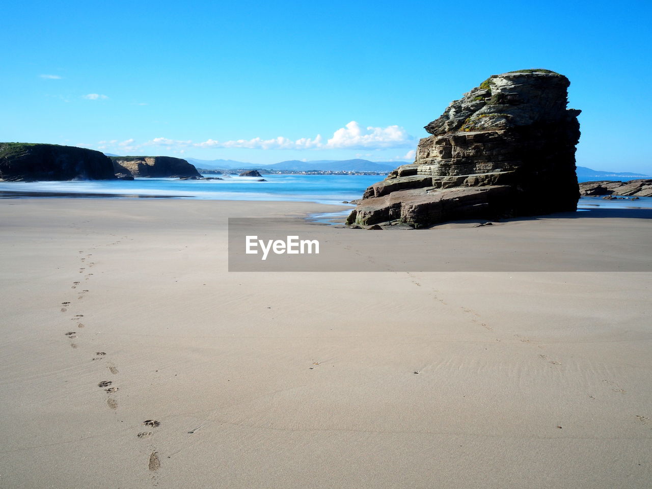 Rock formation at beach against clear blue sky