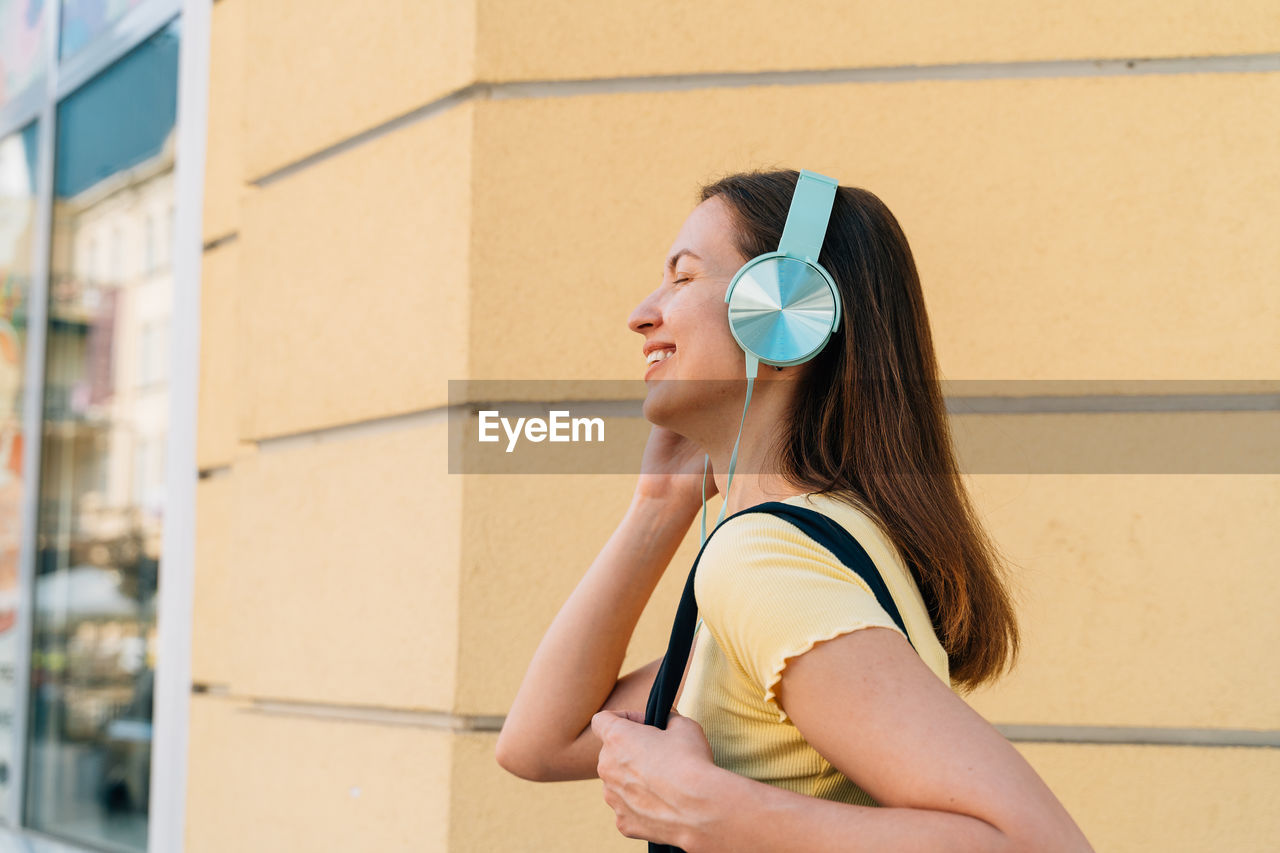 portrait of young woman drinking water while standing in city