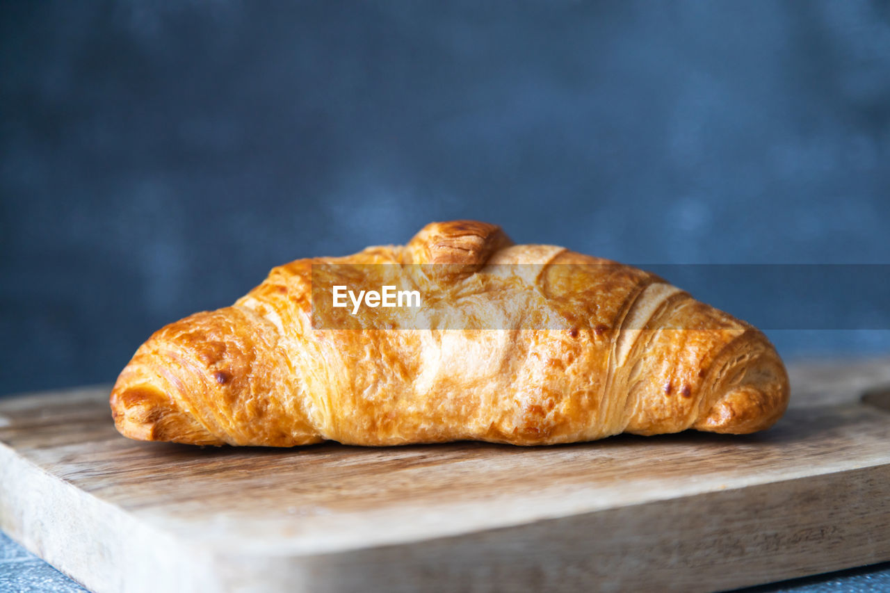 Fresh and juicy croissant on a cutting board on a dark background. place for text. fresh bakery