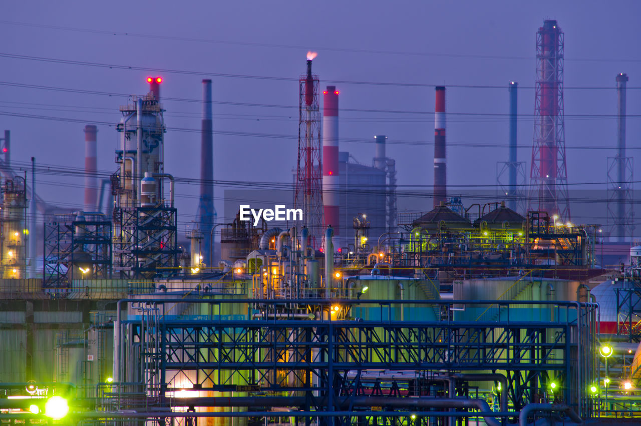 Illuminated factory against sky at night