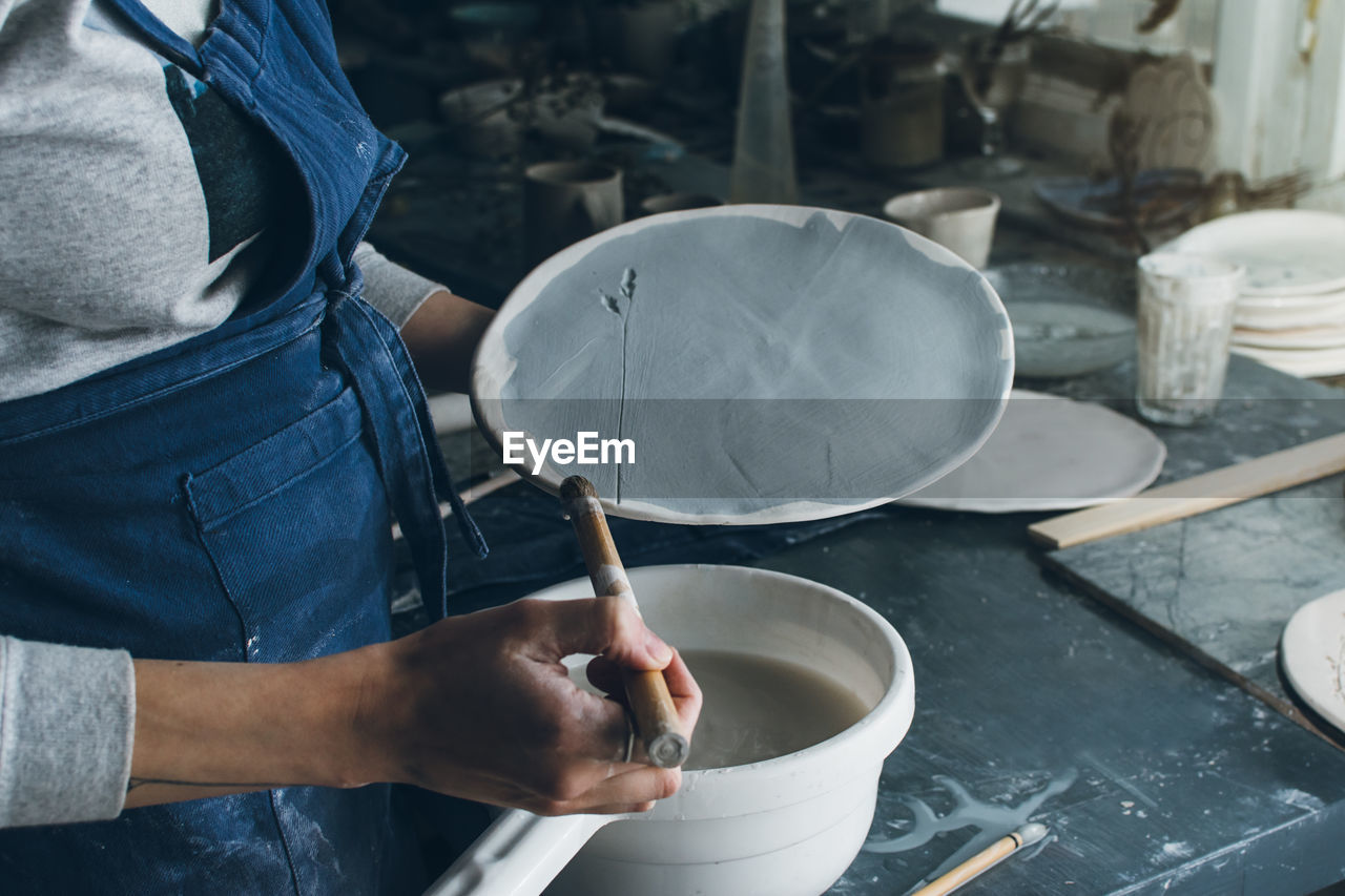 Midsection of woman making art product of clay at workshop