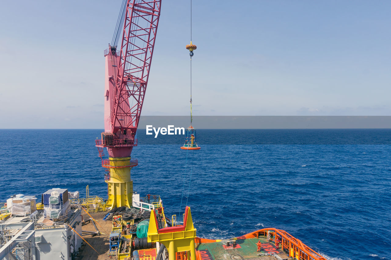 Crane by sea against sky