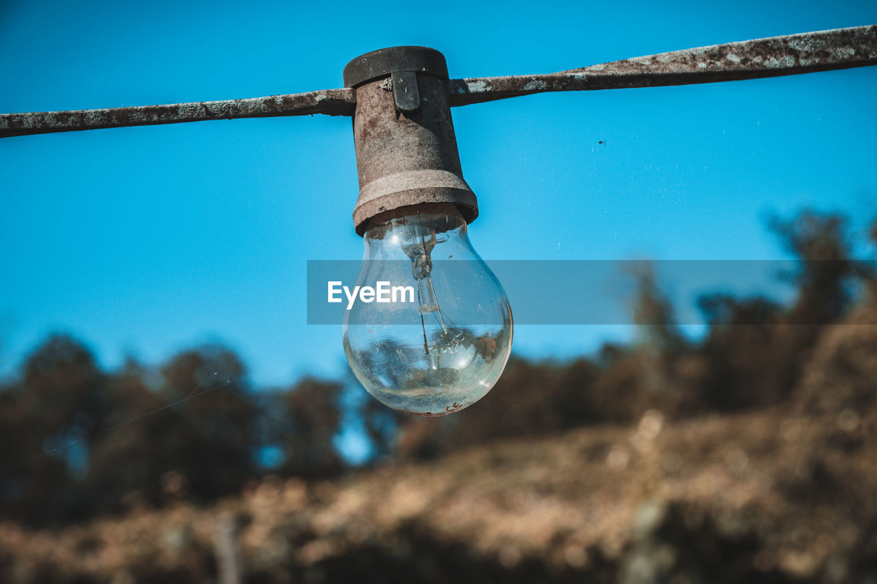 CLOSE-UP OF LIGHT BULB AGAINST CLEAR BLUE SKY