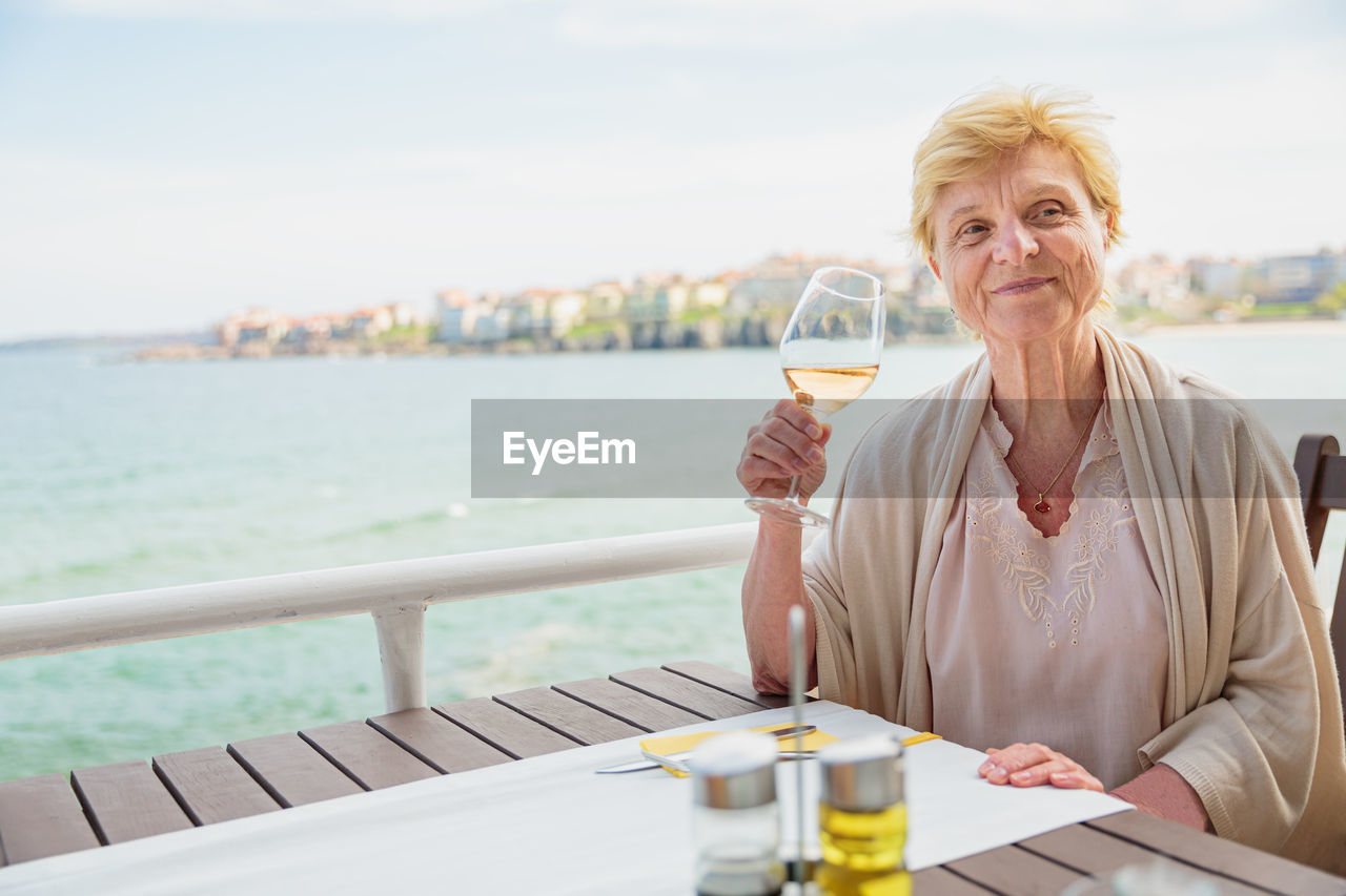 Elderly woman traveler sitting alone on the terrace of coffee shop