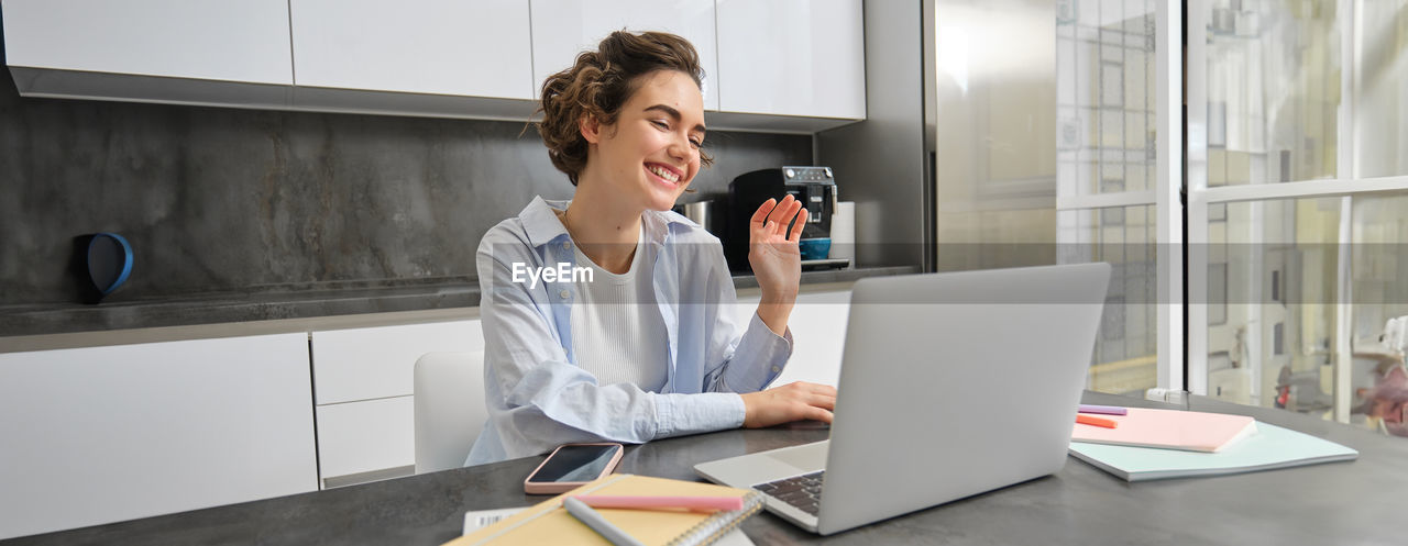 side view of young woman using laptop while sitting on table