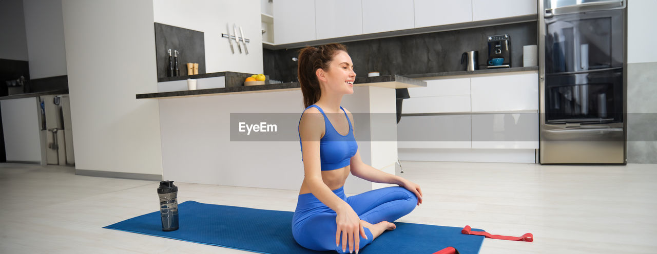 full length of young woman exercising at gym