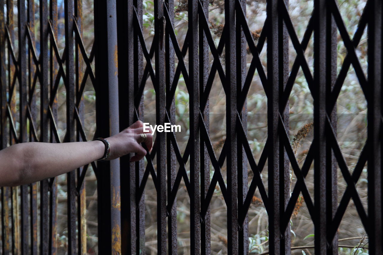 Cropped hand of woman holding fence