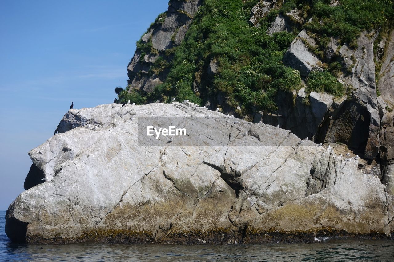 Rocks by sea against sky