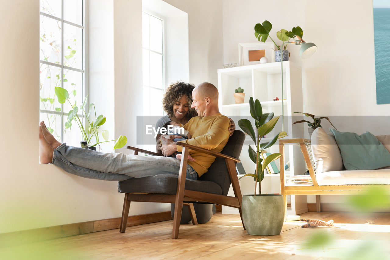 Smiling mother and father looking at their sleeping baby in living room